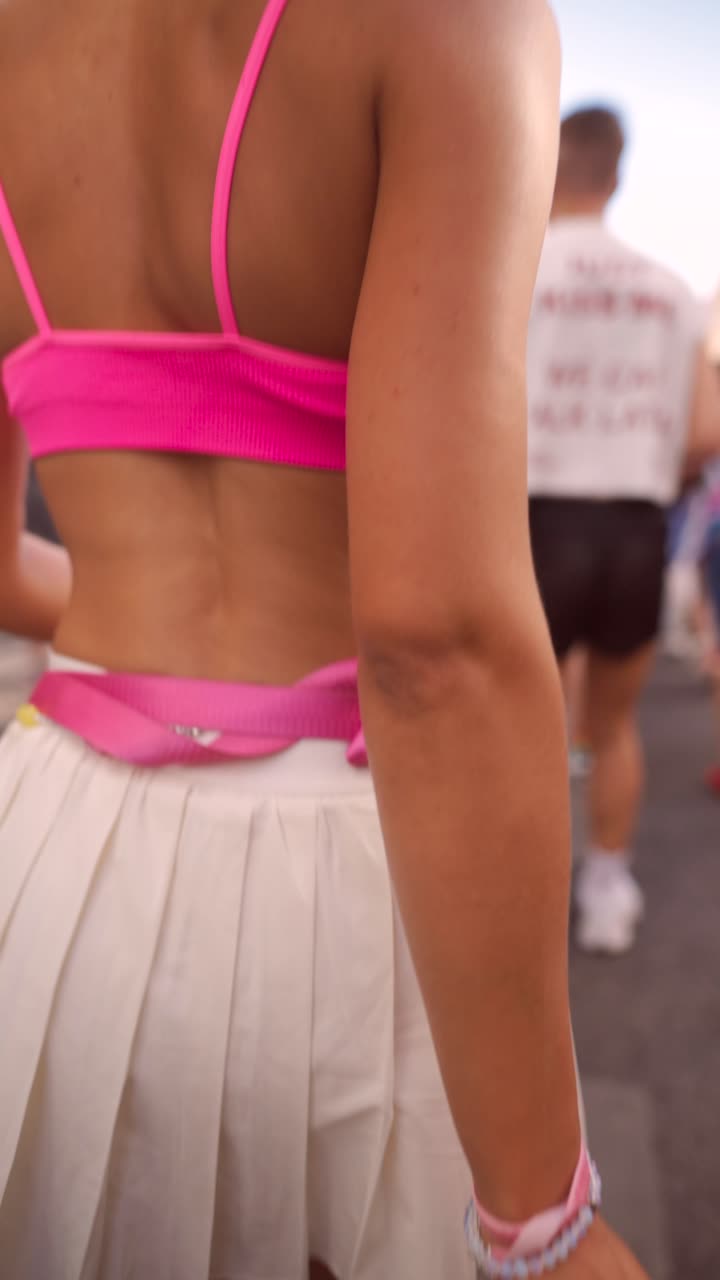 Woman in pink crop top and white pleated skirt