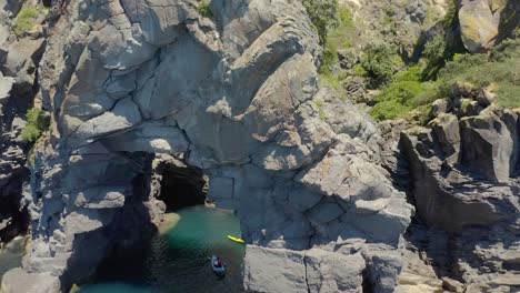 aerial at whale island in new zealand with kayakers in open shore cave