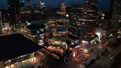 Toma-Descendente-Del-Moderno-Centro-Comercial-Zlote-Tarasy.-Inclinar-Hacia-Arriba-Revela-Los-Rascacielos-Del-Centro.-Escena-De-La-Ciudad-Nocturna.-Varsovia,-Polonia