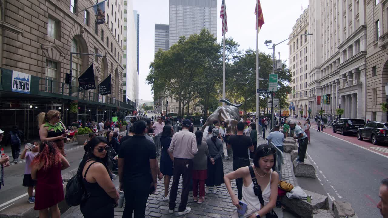 Tourists gather near the famous Charging Bull statue in downtown New York City on a summer day