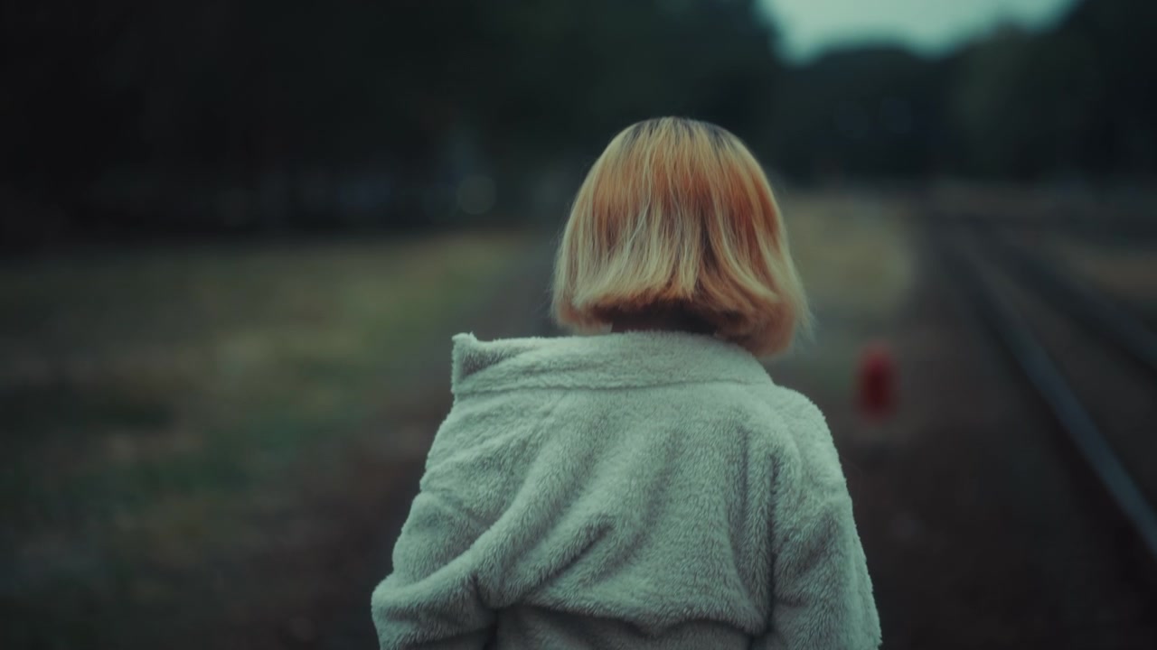 Young Woman with Short Blonde Hair Standing by Train Tracks