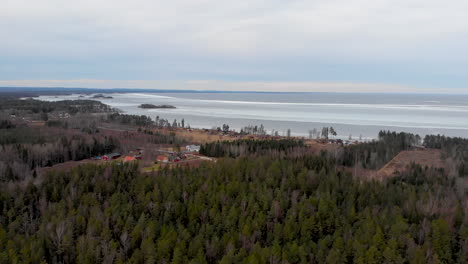 Flying-over-forested-landscape-by-large-Swedish-lake