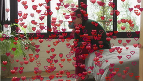 woman sitting on edge bed in bedroom, with heart emojis floating around marketing campaign
