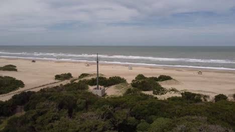 Orbiting-close-up-shot-of-the-green-antenna-in-front-to-the-ocean-which-is-close-to-the-town-beach-at-Mar-de-las-Pampas,-Argentina