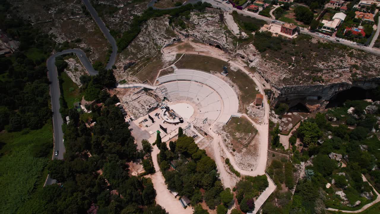 Drone orbit of the Roman ruins in Siracusa, highlighting the historic amphitheater and surrounding park