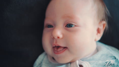 un bebé recién nacido que está sonriendo y acostado sobre un fondo oscuro