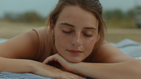a serene portrait of a young woman with freckles relaxing outdoors