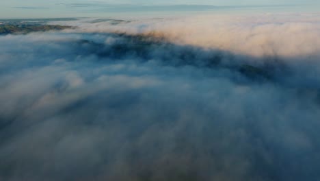 rolling fog sweeps across rural hills and forests in early morning light.