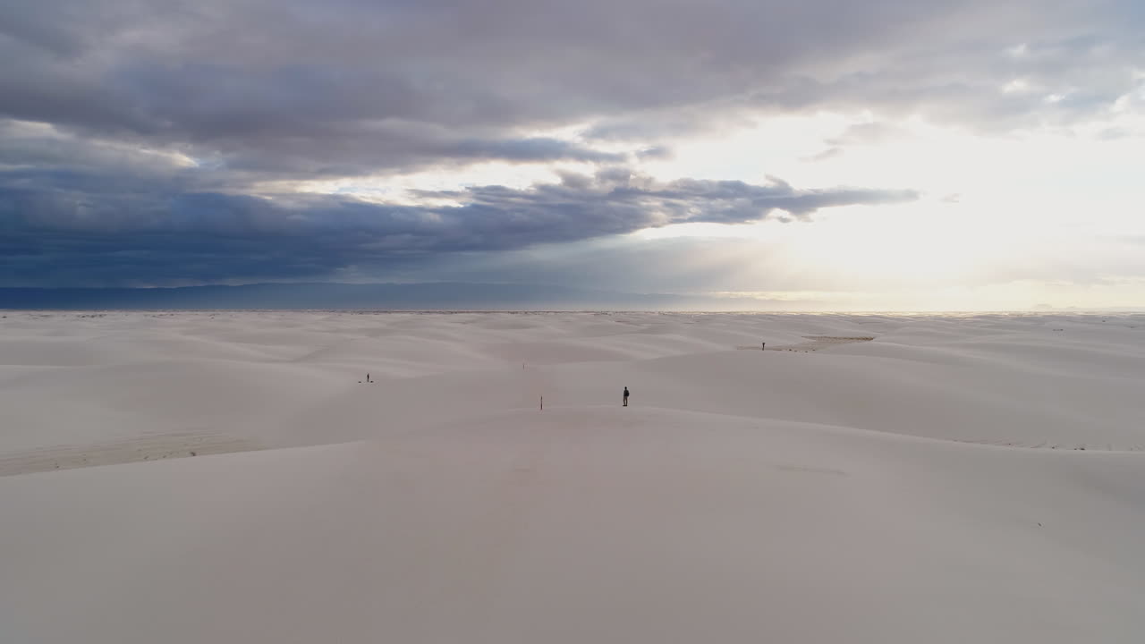 antena en órbita de una persona pequeña en un enorme campo de dunas de arena blanca amanecer, 4k