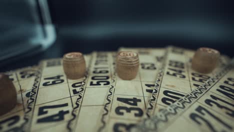 crane slide backwards shot of a bingo desk lottery game, vintage cards with numbers, wooden chips, super slow motion 120 fps, studio lights