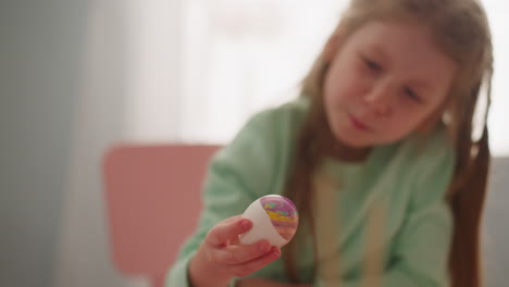 curious girl looks at easter egg with marbling patterns