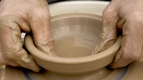 close up of hands working clay on potter.