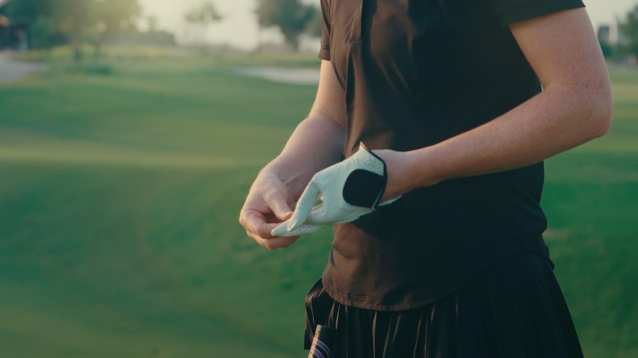 Slow-motion close-up of a female golfer removing her glove one finger at a time. The face is not visible. Focus on detail, texture, and rhythm in a calm moment before or after a shot.