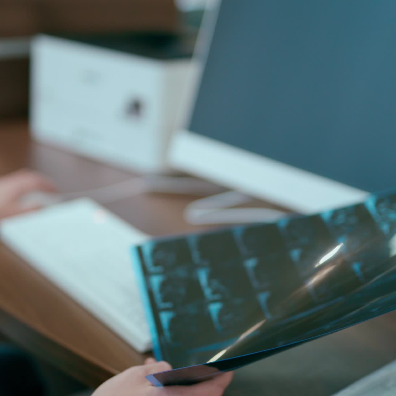 Young doctor holding spine x-ray in clinic. Male specialist sitting in his modern office and talking to somebody. Healthcare concept.