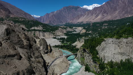 vista aérea cinematográfica de drones del puente ganish sobre el río hunza que fluye a través de las montañas de pakistán