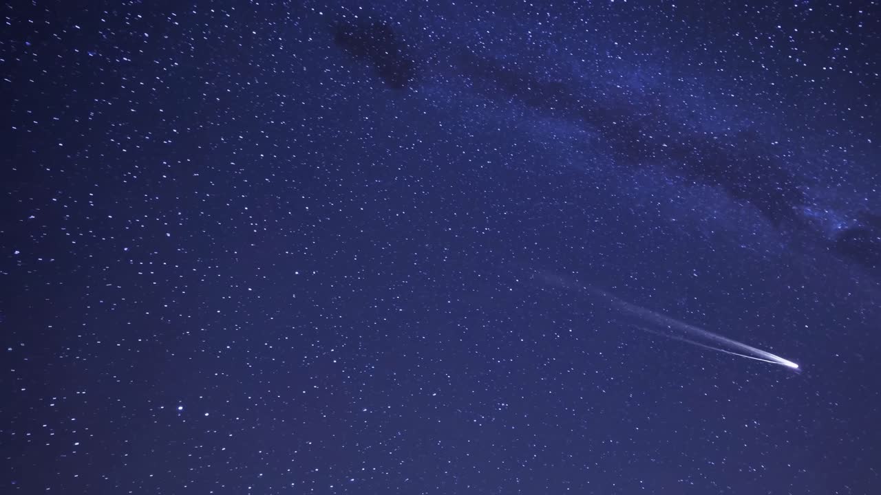 A mesmerizing video of a starry night sky with a shooting star, captured from a low-angle