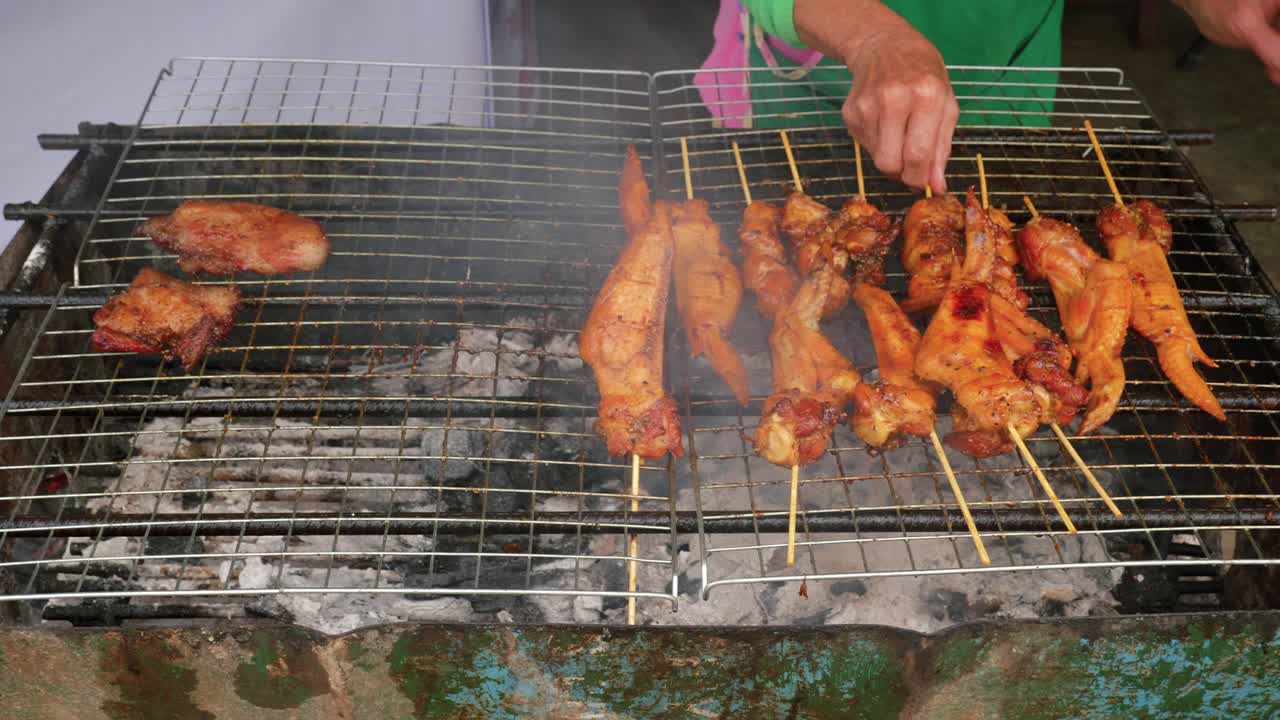 cerrar el pollo marinado en un palo girado y asado por un vendedor ambulante, tailandia