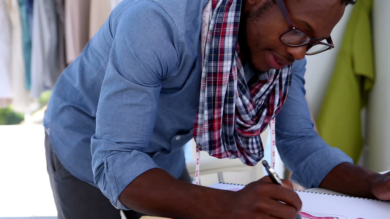 Cheerful fashion designer drawing clothes with a pencil