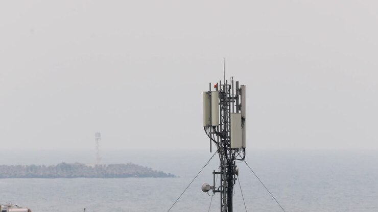 Antenna di una torre di rete cellulare sulla costa marina con paesaggio marino nella nebbia sullo sfondo.