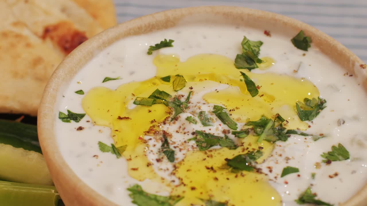 Greek Tzatziki sauce of salted strained yogurt or diluted yogurt mixed with cucumbers and mint, garlic, salt, olive oil on top. High quality 4k footage