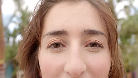 retrato de una feliz mujer caucásica mirando a la cámara sobre las palmeras.