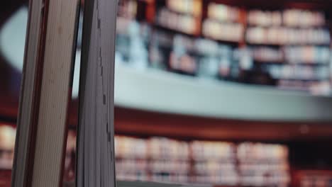 a close-up of book pages in the foreground with a blurred background of a modern, curved library shelf full of books—symbolizing knowledge and depth of information