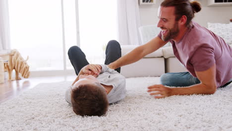 Padre-Haciéndole-Cosquillas-A-Su-Hijo-Mientras-Juegan-Juntos-En-El-Salón.