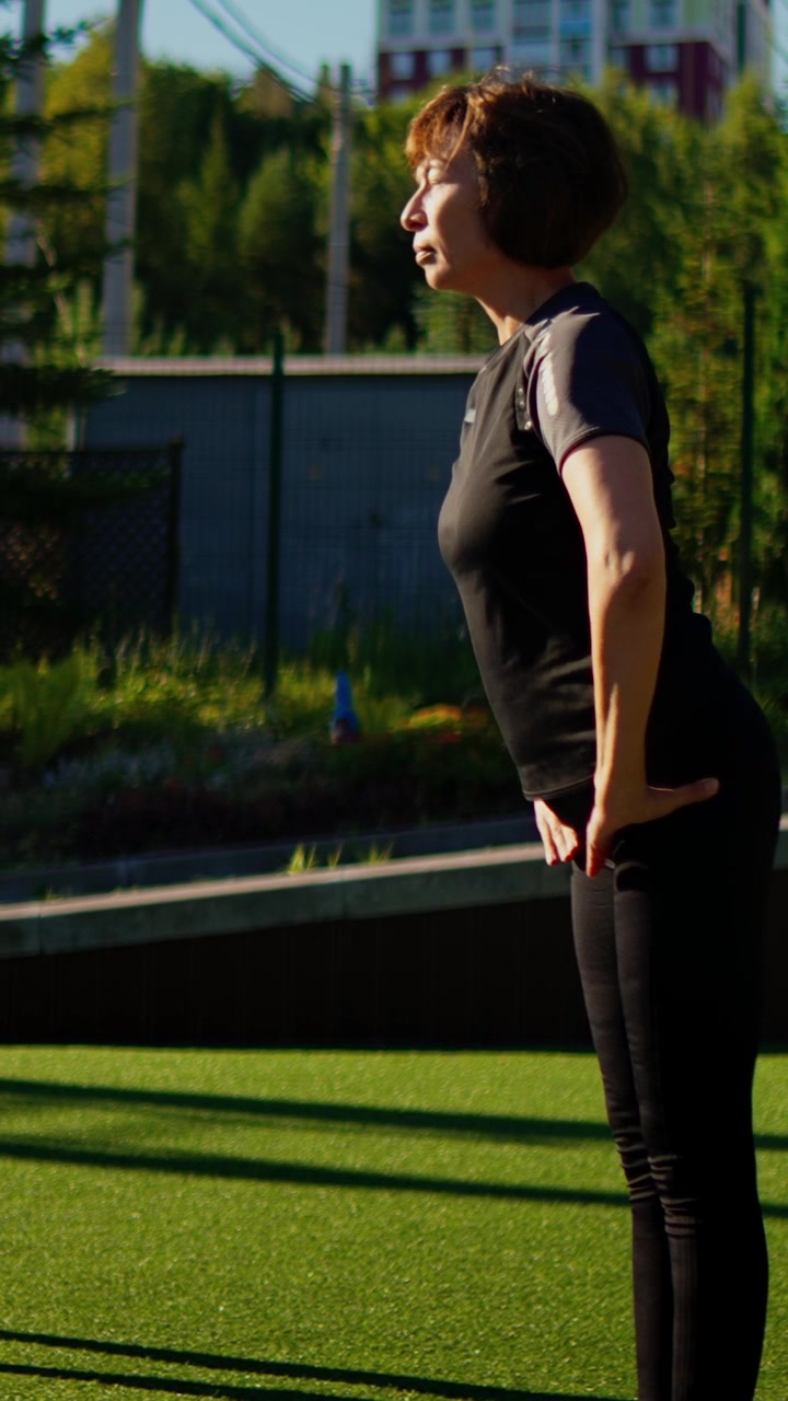 Donna matura che pratica yoga e stretching all'aperto in un parco