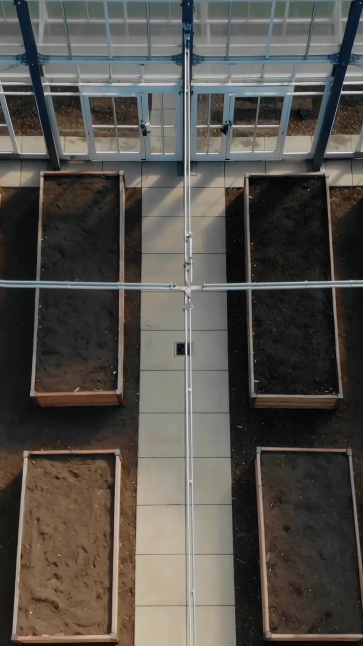 Video verticale: Partendo dall'alto, telecamera che scende al centro di una serra, rivelando fioriere e un percorso.