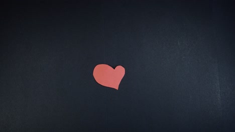 woman's hand writing "love" on heart shaped red paper. shot from above with the sony a7iii.