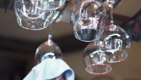 empty washed glasses putting into its position with a white rifle above the bar counter at the restaurant. wine glasses