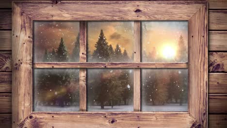 wooden window frame against snow falling over multiple trees on winter landscape