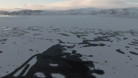 Dolly-forward-above-frozen-lake-and-majestic-mountains-in-background