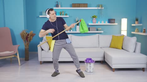 el hombre que se sumerge en la música que escucha mientras limpia su casa y comienza a bailar y hacer movimientos divertidos.