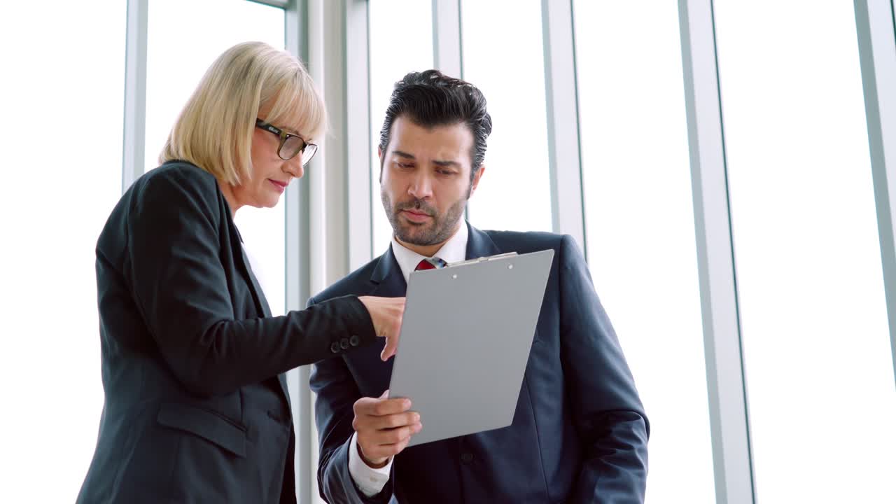 Two business people talk project strategy at office