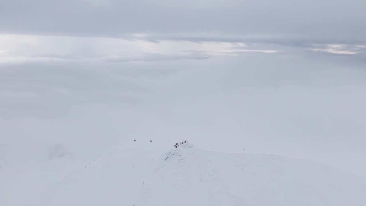 Aerial drone view of people hiking on Ciucas peak covered in snow in winter season. Romania, Carpathian Mountains