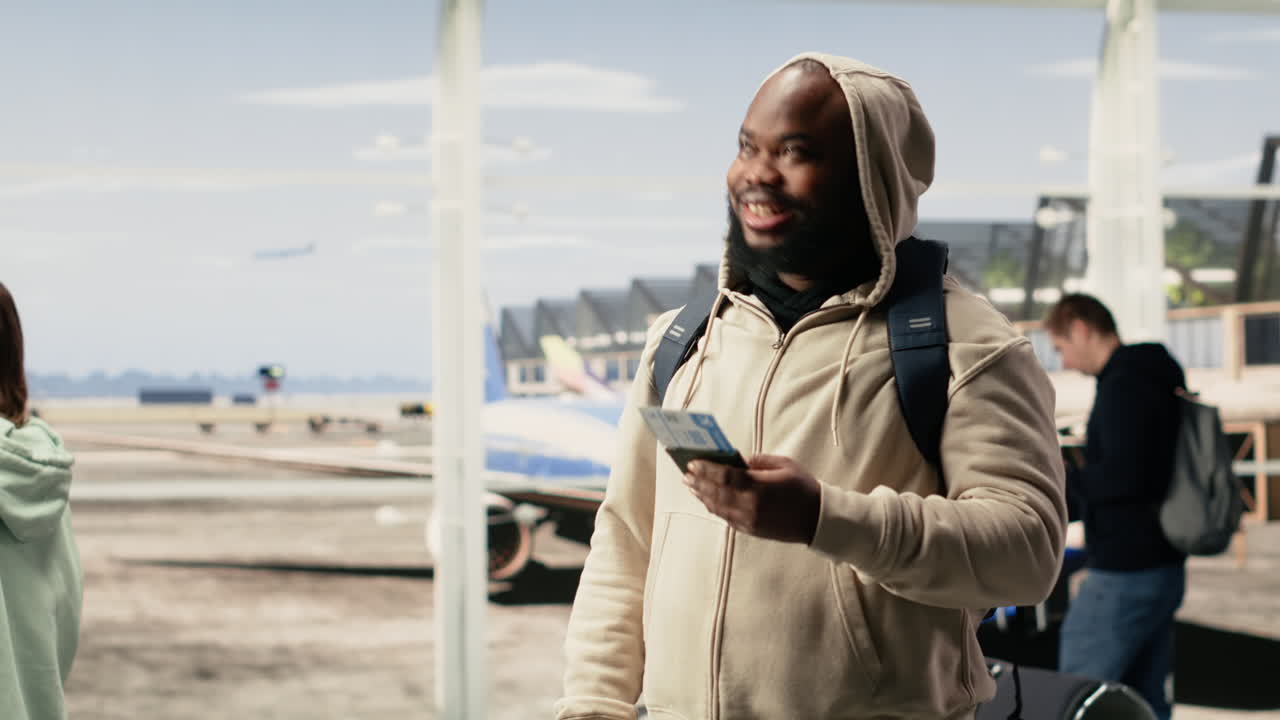 Uomo felice che cammina nel terminal dell'aeroporto con una valigia