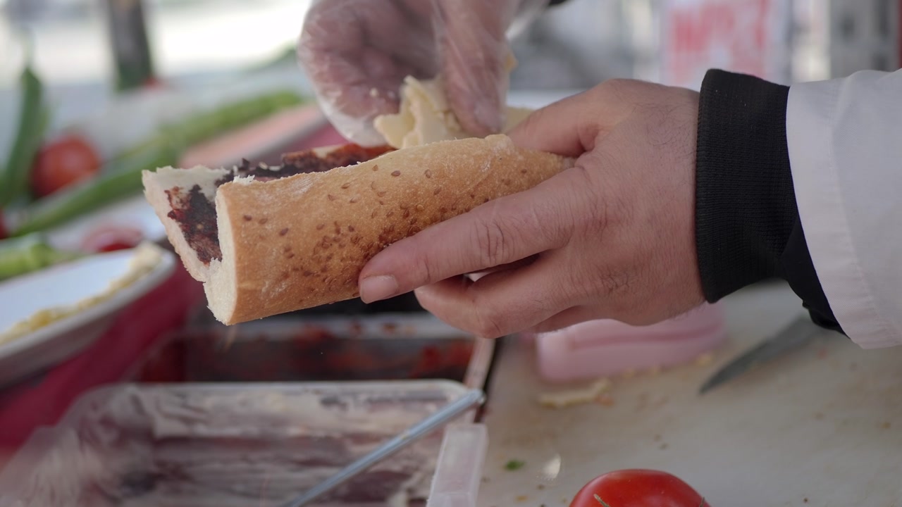 Street Food Vendor Assembling a Savory Baguette Sandwich