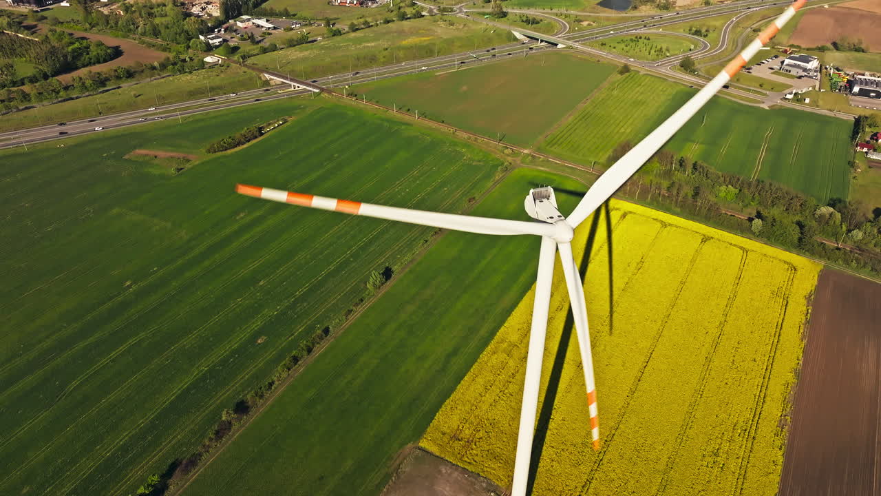 Towering Wind Turbines Over Canola Fields Near Countryside Town. Aerial Drone Shot
