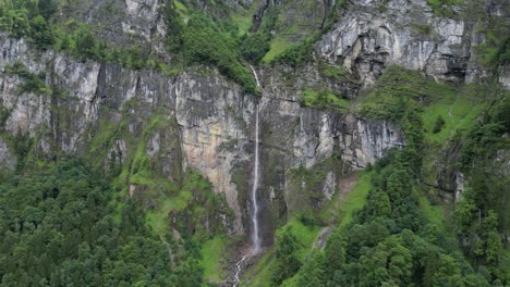 hermosa cascada en cascada desde el terreno rocoso de los alpes suizos, aero