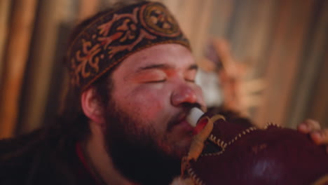 tired man in national altai clothes drinks from waterskin