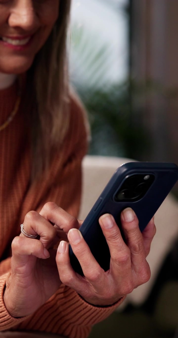 Donna che usa lo smartphone mentre si rilassa a casa