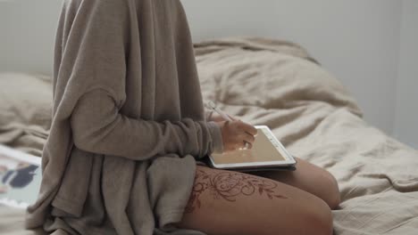 woman drawing on a tablet in bed