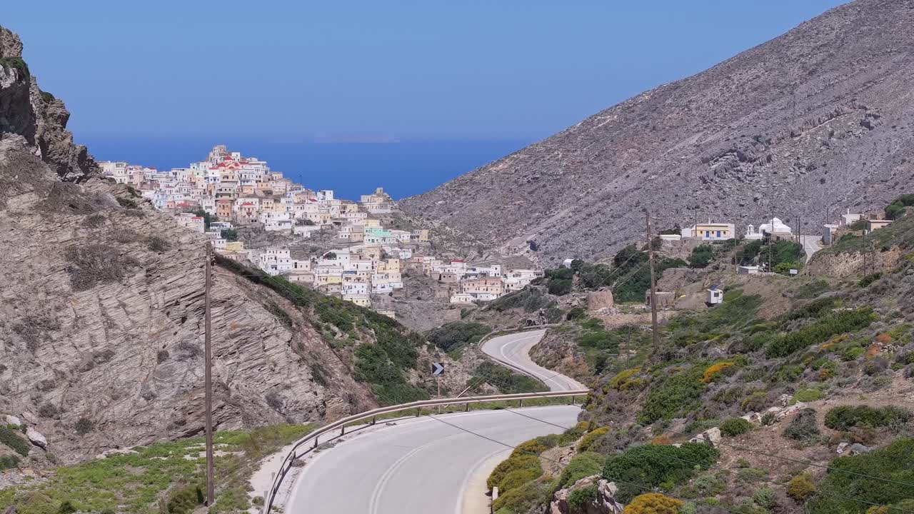 Aerial drone footage revealing the picturesque Olympos Village hidden behind a hill on Karpathos Island, Greece — showcasing its traditional charm and scenic mountain location