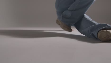 studio shot of young woman having fun break dancing against grey background