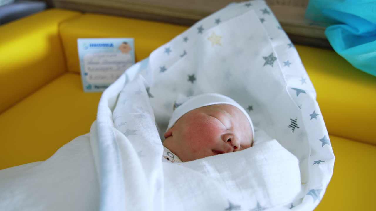 Peacefully sleeping Caucasian baby in a cute cap. Adorable newborn child in a blanket close up.