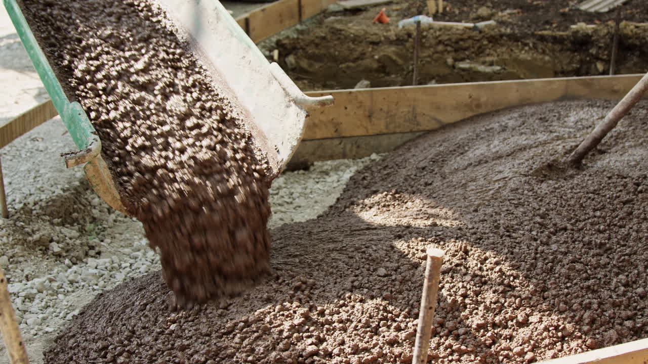 Workers Pouring and Spreading Fresh Concrete on a Construction Job Site