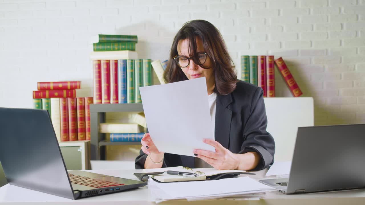 una mujer de negocios de 40 años revisa informes o formularios de impuestos, encuentra errores totales y tira estos documentos