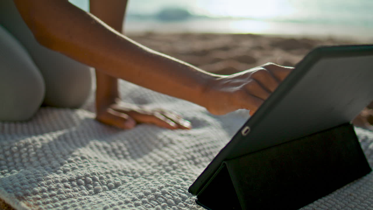 niña usando tableta playa de cerca. mujer poniendo tableta computadora en la alfombra de yoga.