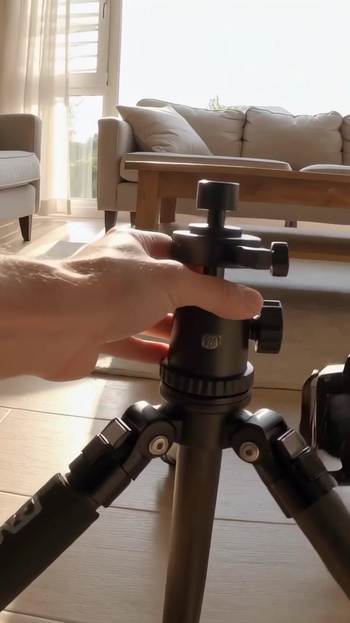 Vertikal video: Persons hænder kommer ind i billedet, monterer stativ og fastgør et DSLR-kamera i stuen.